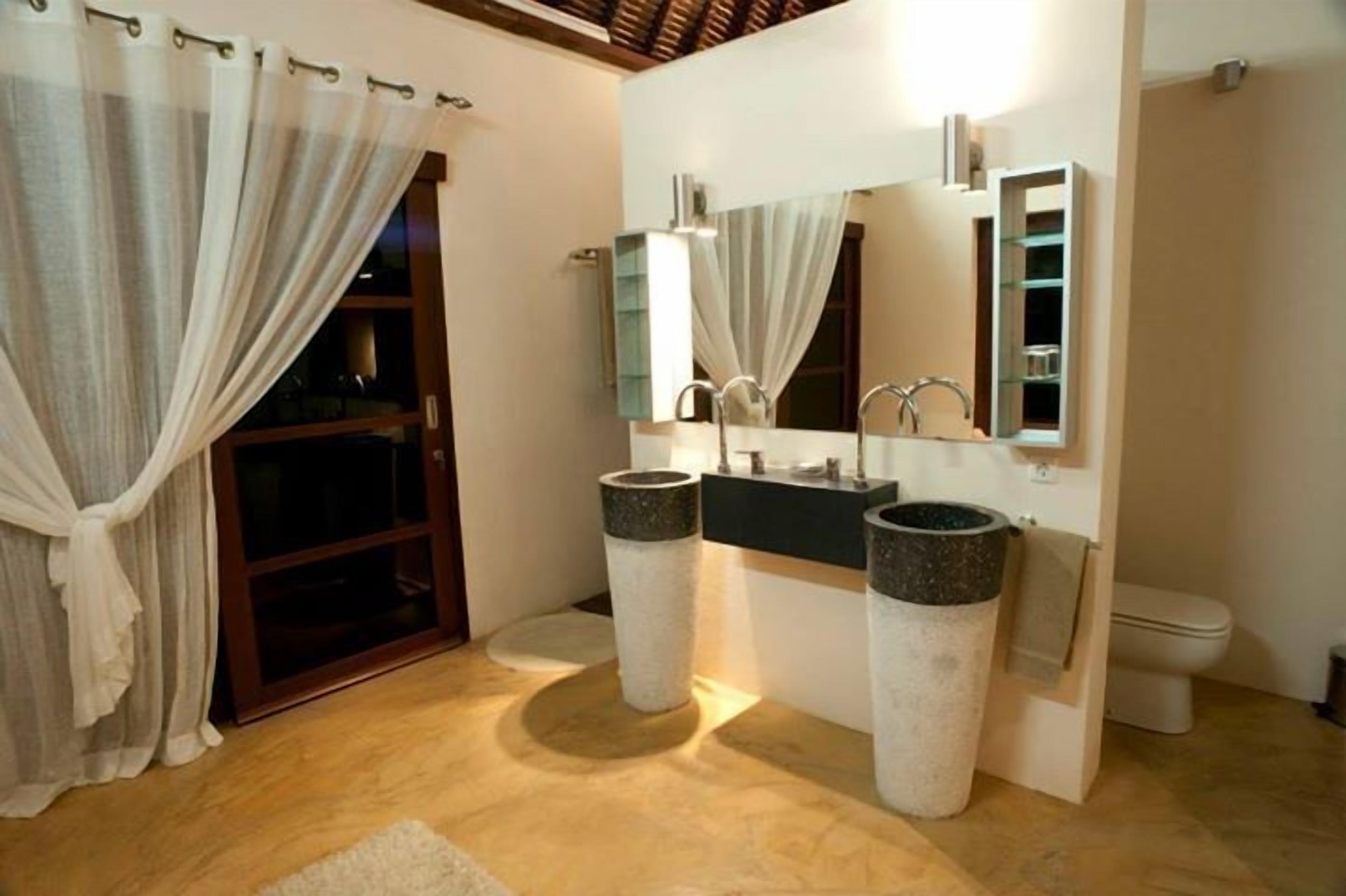 A modern bathroom with a double sink, a large mirror, and a toilet.