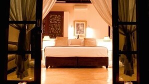 A bedroom with a bed, bedside lamps, and a nightstand. - Chuiba Bay Lodge (Pemba)