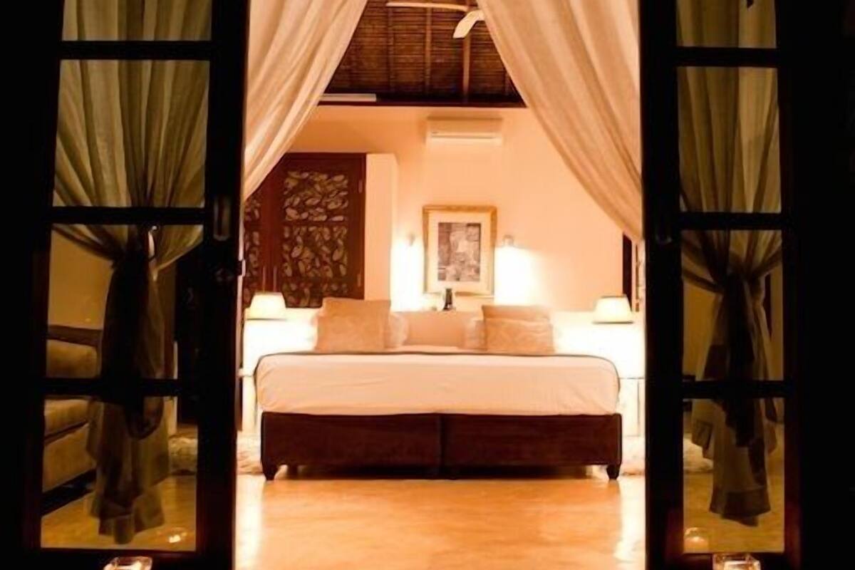 A bedroom with a bed, bedside lamps, and a nightstand.