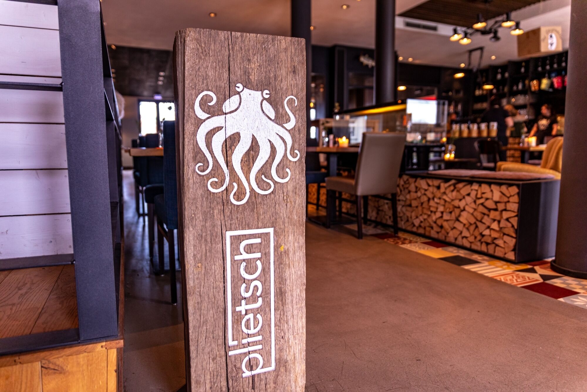 Un letrero de madera con un logotipo y el nombre 'eleftsch' en un interior moderno con una zona de bar.