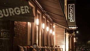 A restaurant with outdoor seating, a sign reading "BURGER," and a "pliets" sign above. - Krögers Hotel (Esens)