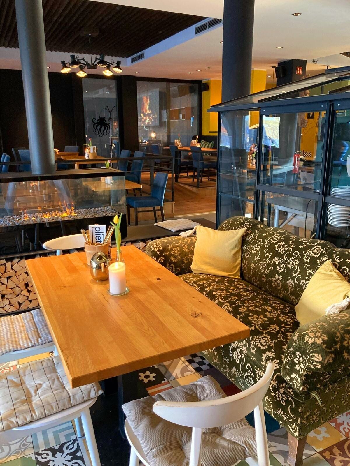 Un intérieur moderne avec une table en bois, un canapé à motifs et une cloison en verre.