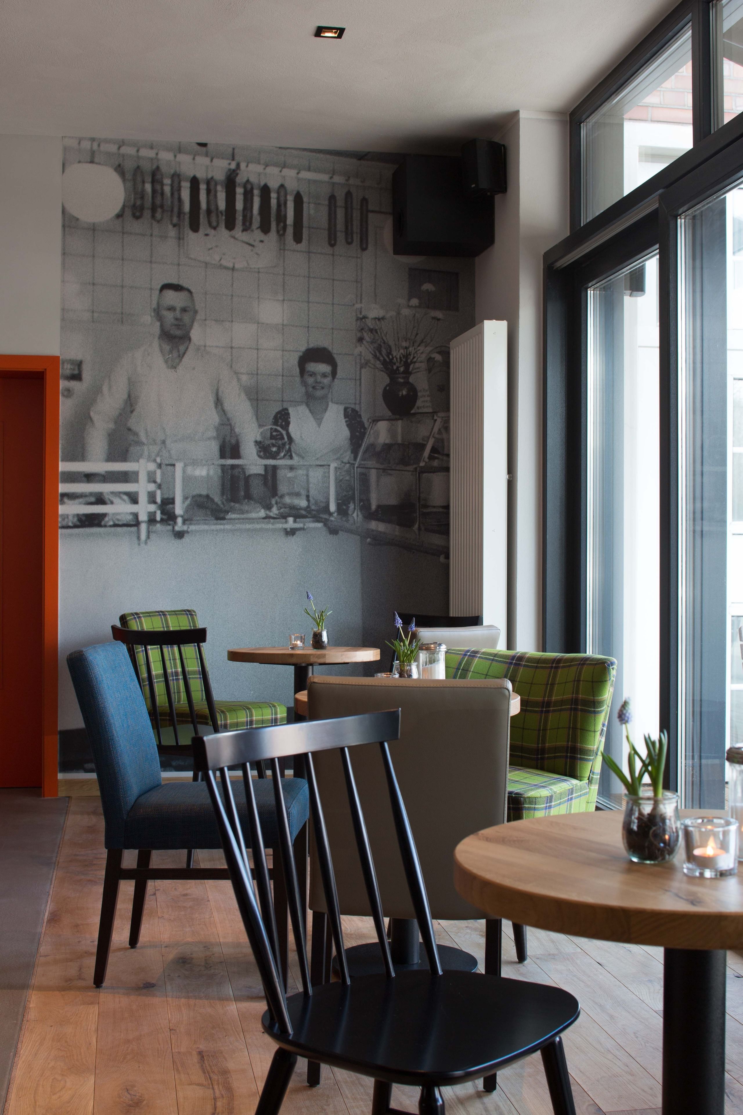 A modern dining area with a mural, wooden tables, and chairs.