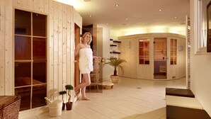 A wooden spa room with sliding glass doors, a small potted plant, and a bench. - Krögers Hotel (Esens)