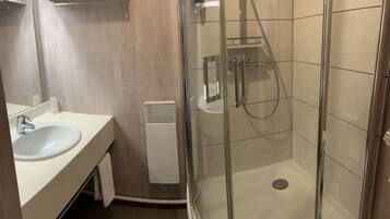 A modern bathroom with a glass-enclosed shower, a white sink, and a mirror.