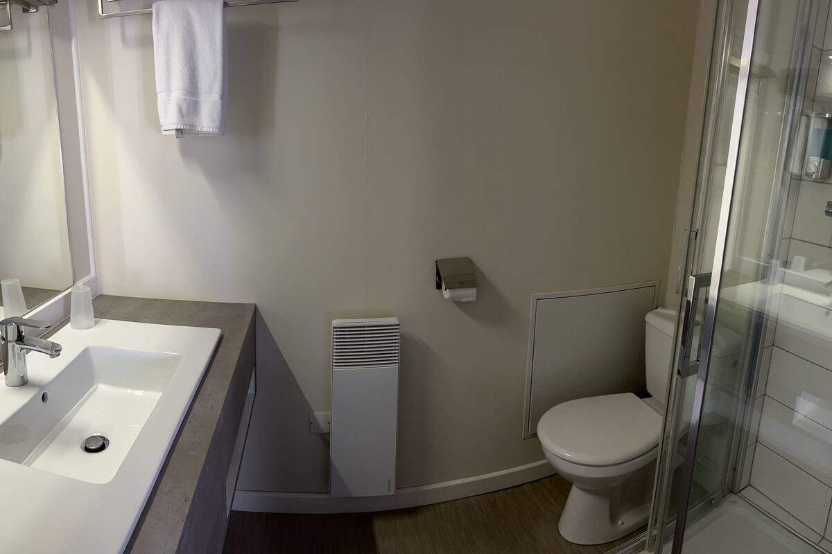Ein modernes Badezimmer mit Waschbecken, Spiegel und Toilette in Weiß.