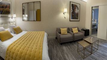 Una habitación de hotel con cama, sofá, mesita y espejo.