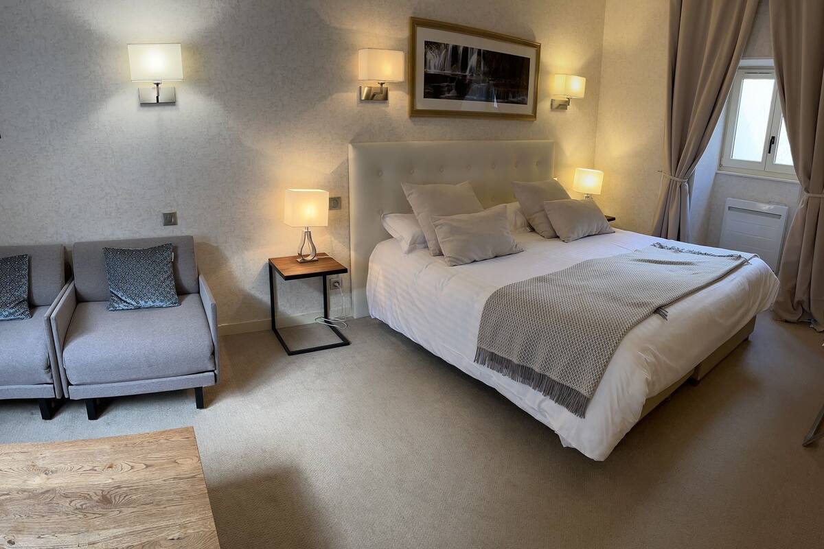 Ein Hotelzimmer mit Bett, Sofa, Nachttisch und Lampe.