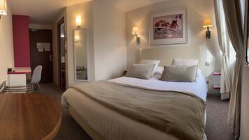 Een hotelkamer met een groot bed, een bureau, een stoel en een spiegel.