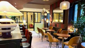 Un restaurante con zona de bar, varias mesas y sillas, y lámparas colgantes.
