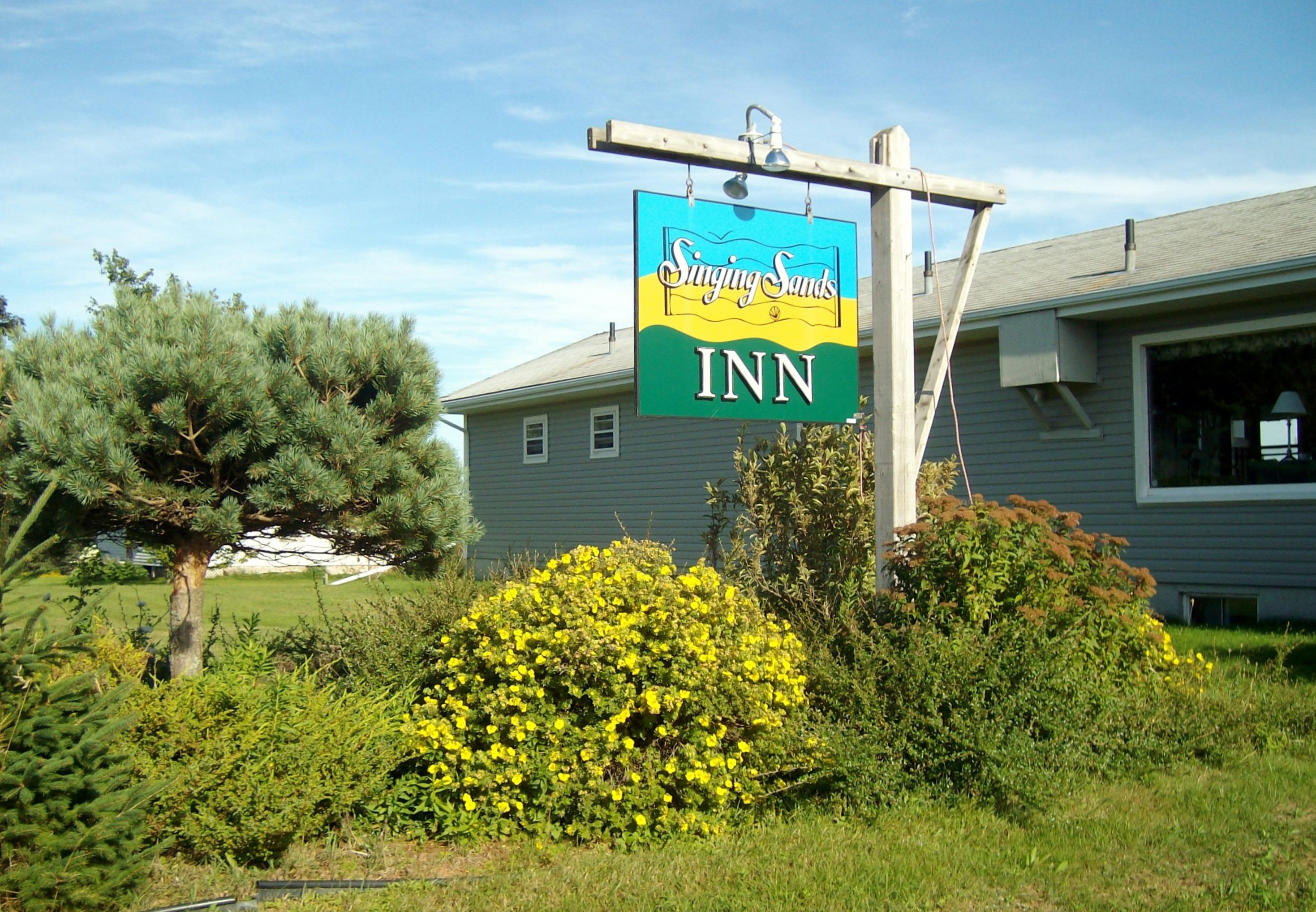 A sign for Singing Sands Inn with a clear view of the building's exterior.