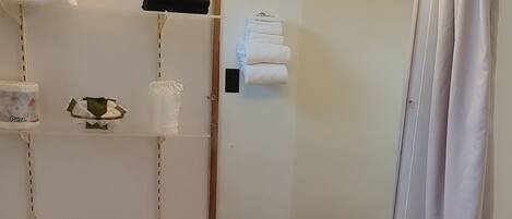 A bathroom with a toilet, sink, and shower. There are towels and a mirror on the wall.