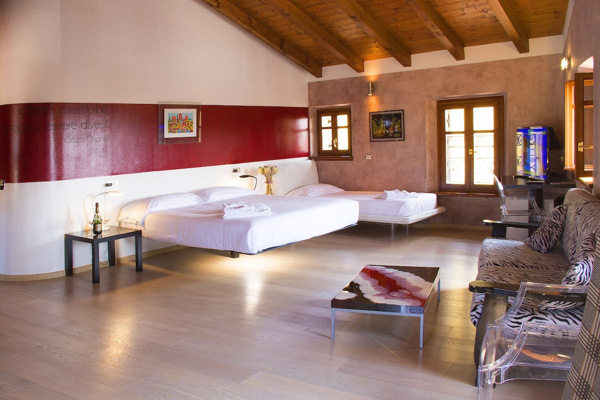 A hotel room with a large bed, a smaller bed, a sofa, and a table.