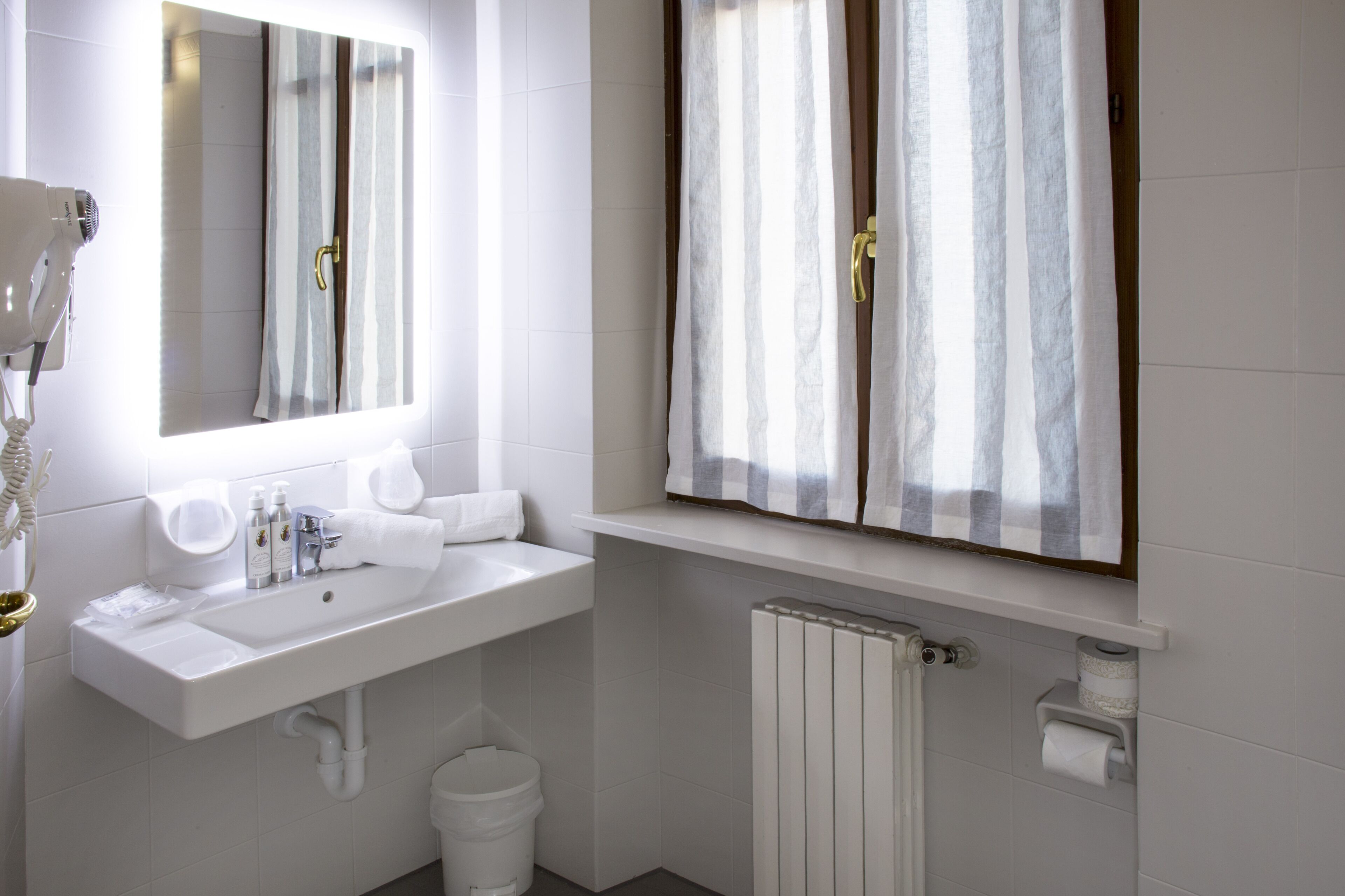 A modern bathroom with a white sink, mirror, and shower curtain.