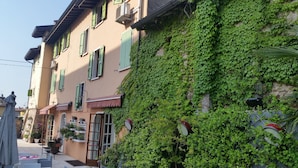 Un bâtiment aux volets verts, doté d’une marquise rouge et dont le mur est recouvert de lierre.