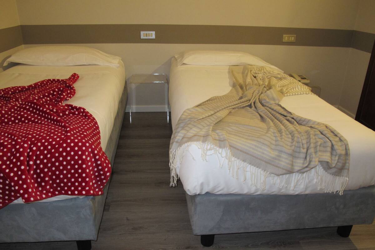 Two single beds with white linens and a small bedside table between them.