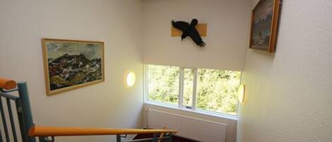 Una escalera con alfombra roja, una decoración de pájaro negro en la pared y un cuadro enmarcado.
