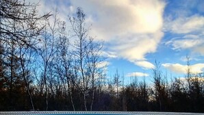 A swimming pool with clear blue water, surrounded by trees and a partly cloudy sky. - Hotel Kjarnalundur (Akureyri)