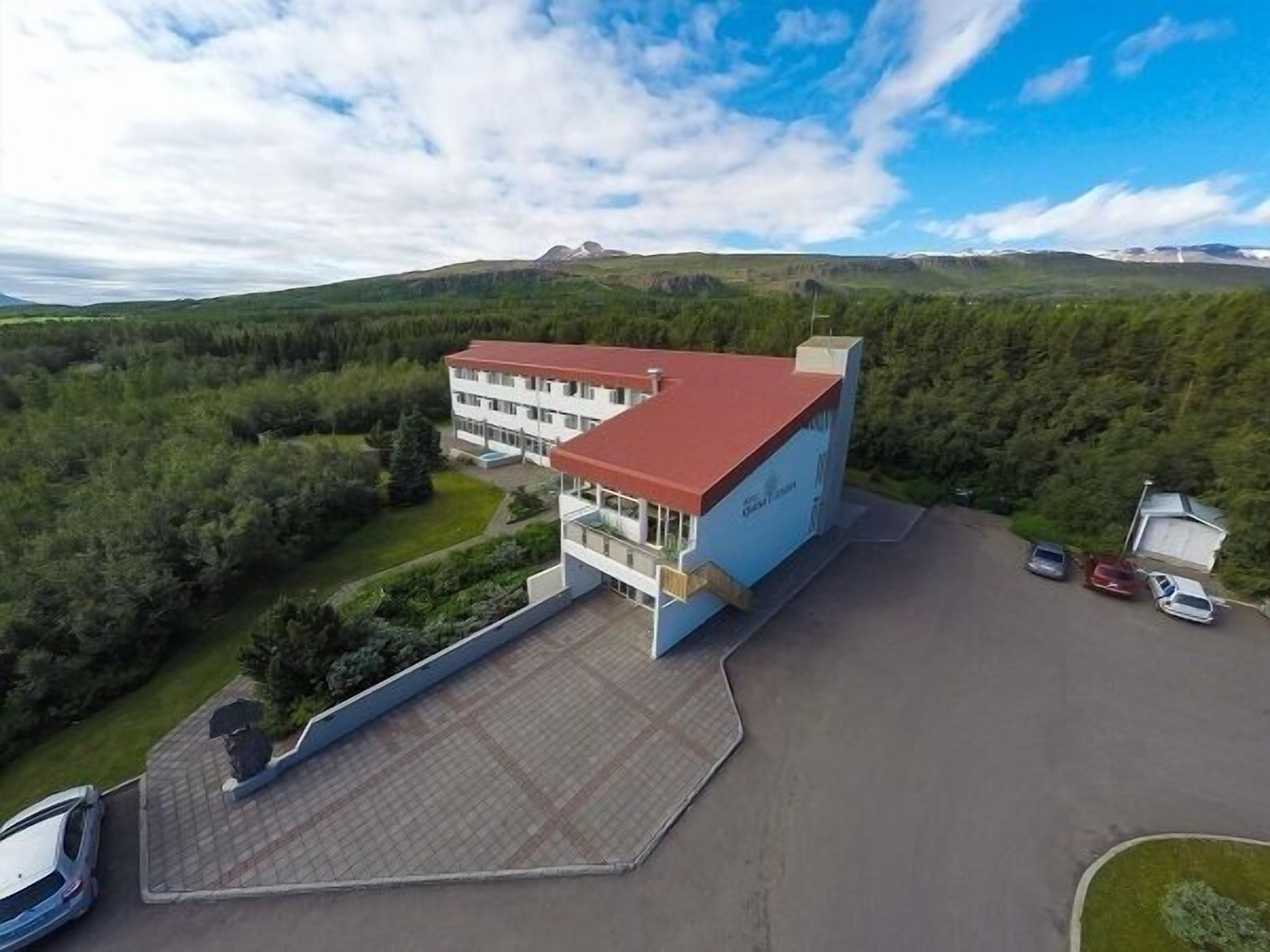 Un hotel de varios pisos con tejado rojo, rodeado de exuberante vegetaci ón y colinas.