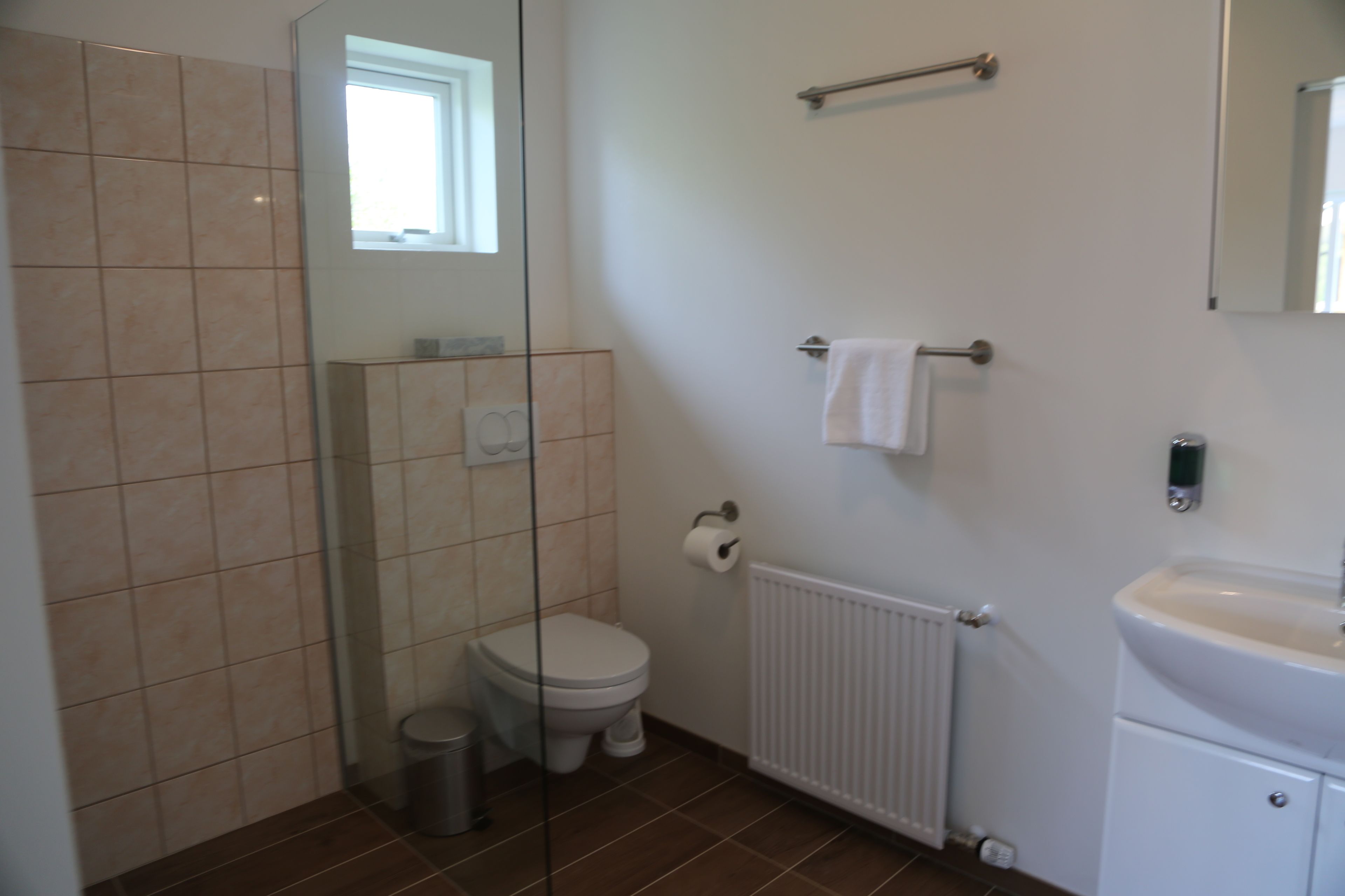 A bathroom with a toilet, a sink, a towel rack, and a window.