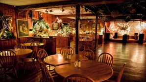 Un restaurante acogedor con interiores de madera, mesas redondas y sillas.