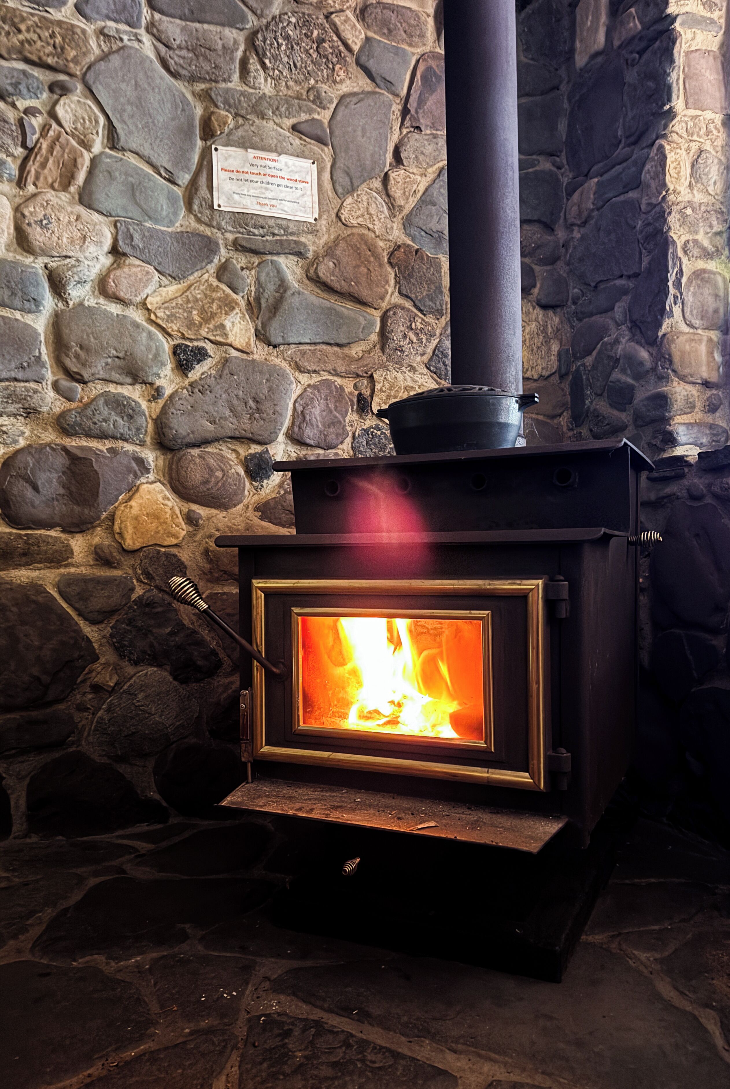 A wood-burning stove with a stone wall background and a sign above it.