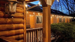 Una cabaña de troncos con una terraza de madera y un letrero que indica la entrada.