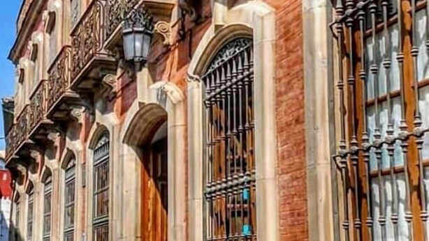 Un edificio histórico con detalles arquitectónicos ornamentados, incluyendo balcones decorativos y ventanas en arco.