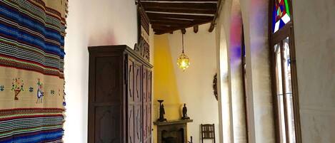A hallway with a checkered floor, a wooden cabinet, a hanging light fixture, and a stained glass window.