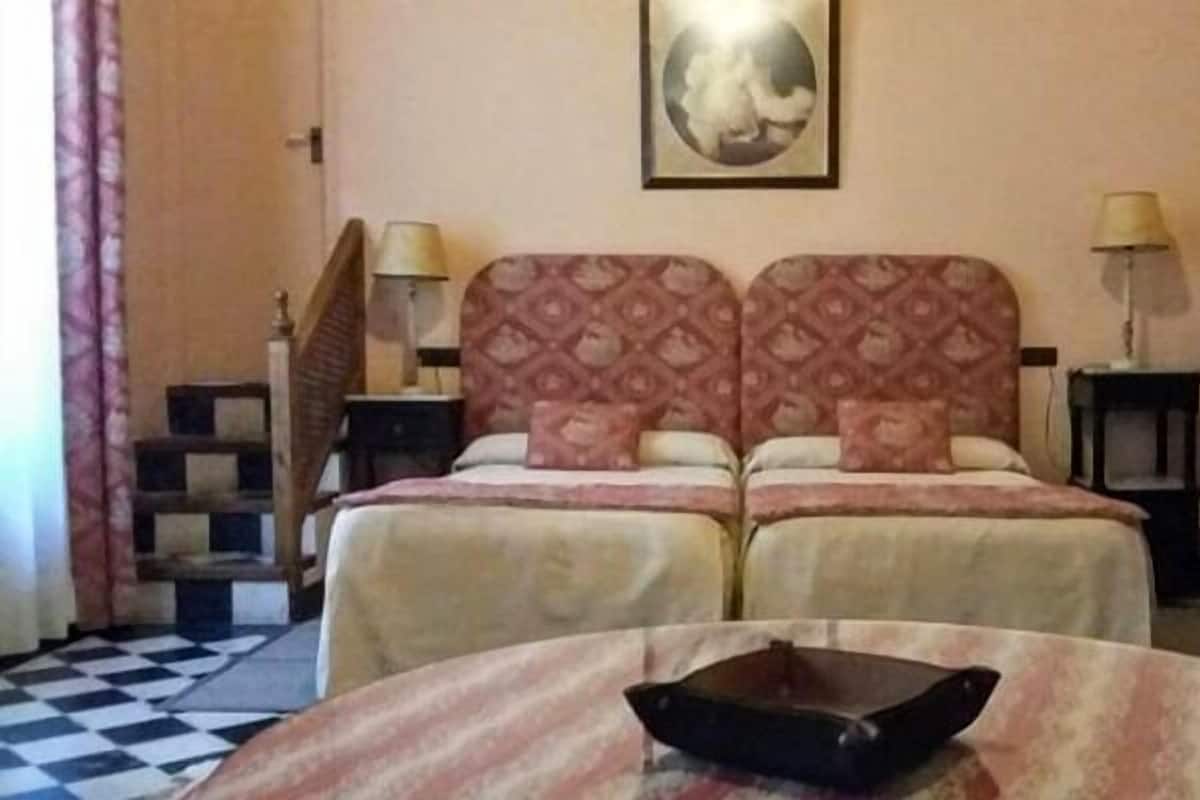 Una cama doble con un cabecero estampado, una mesita con un cuenco y un suelo a cuadros.