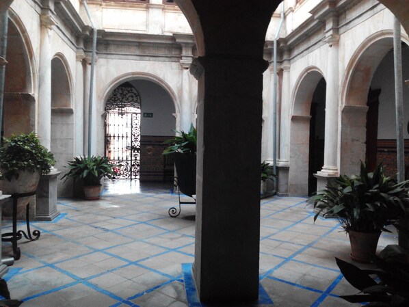 A courtyard with tiled flooring, potted plants, and a central column. - Hotel Ordoñez Sandoval (Úbeda)
