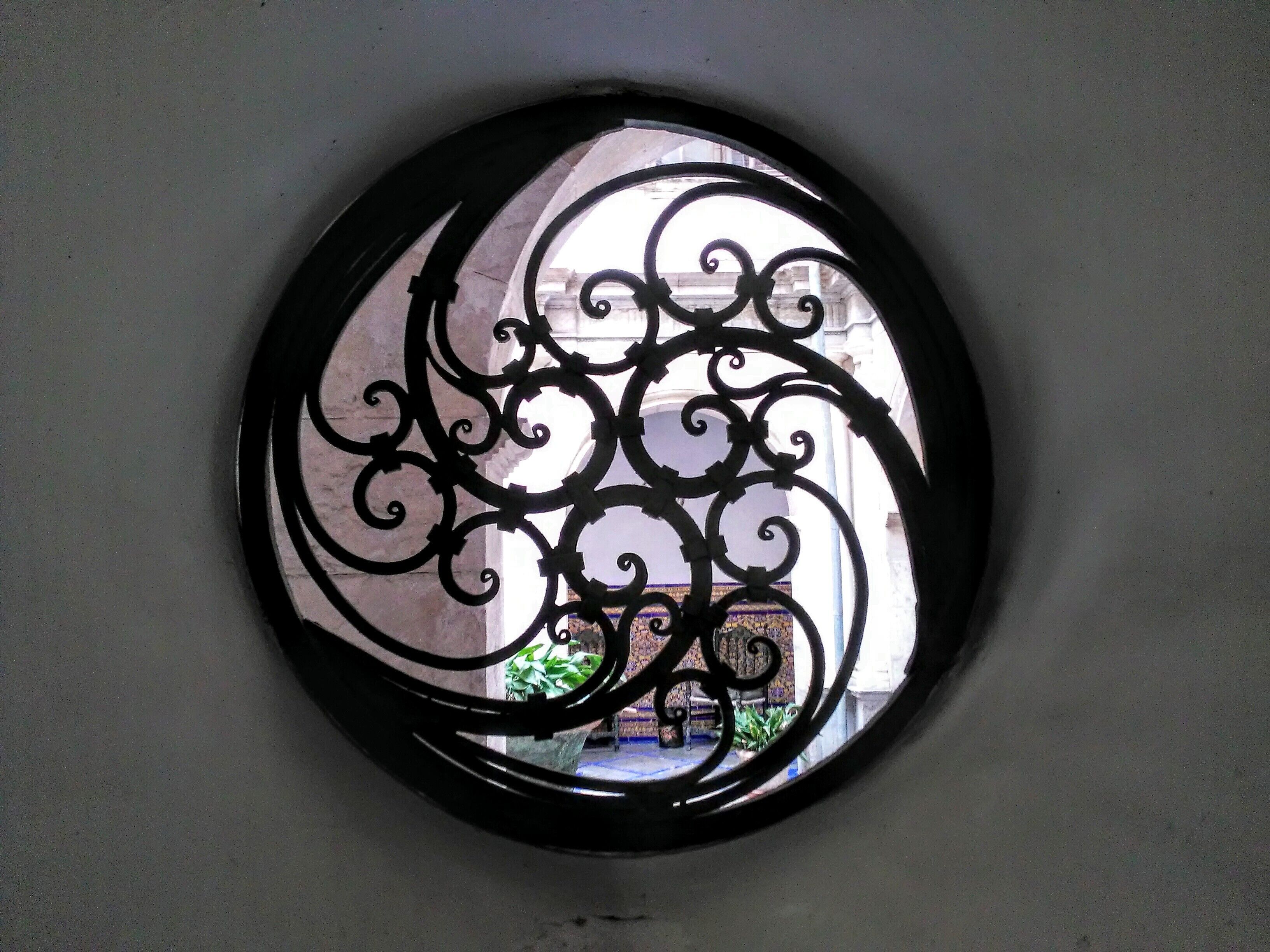 Een rond raam met versierde zwarte metalen decoratie.