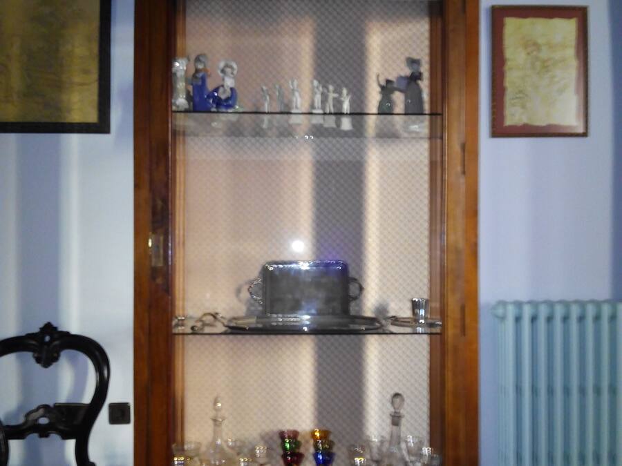 Un aparador de madera con varias repisas que contienen cristalería y figuritas.