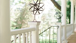 Un porche de madera con barandillas blancas y un móvil decorativo de metal.