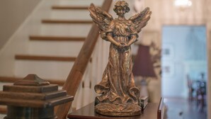 Una escalera con una estatua de un ángel sobre una mesa de madera al final.