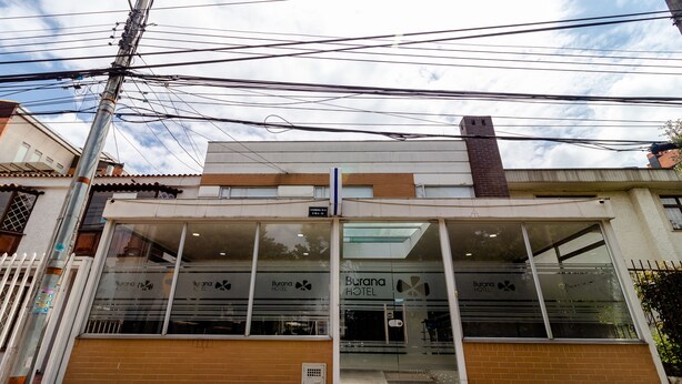 A hotel entrance with a glass facade, a sign reading "Burano Hotel," and a visible entrance door. - Hotel Burana (Bogotá)