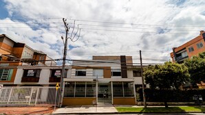 A modern building with a glass facade, a gated entrance, and a visible street sign. - Hotel Burana (Bogotá)