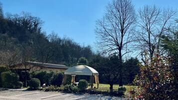A gazebo in a garden with a clear sky and trees in the background.