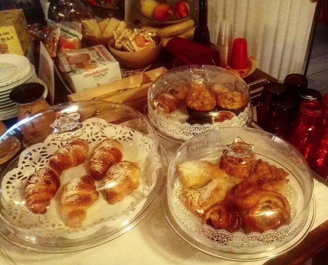 Una mesa con diversos alimentos, incluyendo pasteles y pan, cubiertos con campanas de cristal.