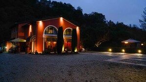 A house with a gravel driveway, a covered patio, and a small adjacent structure with lights. - Country Home B&B Il Melo (Vicenza)