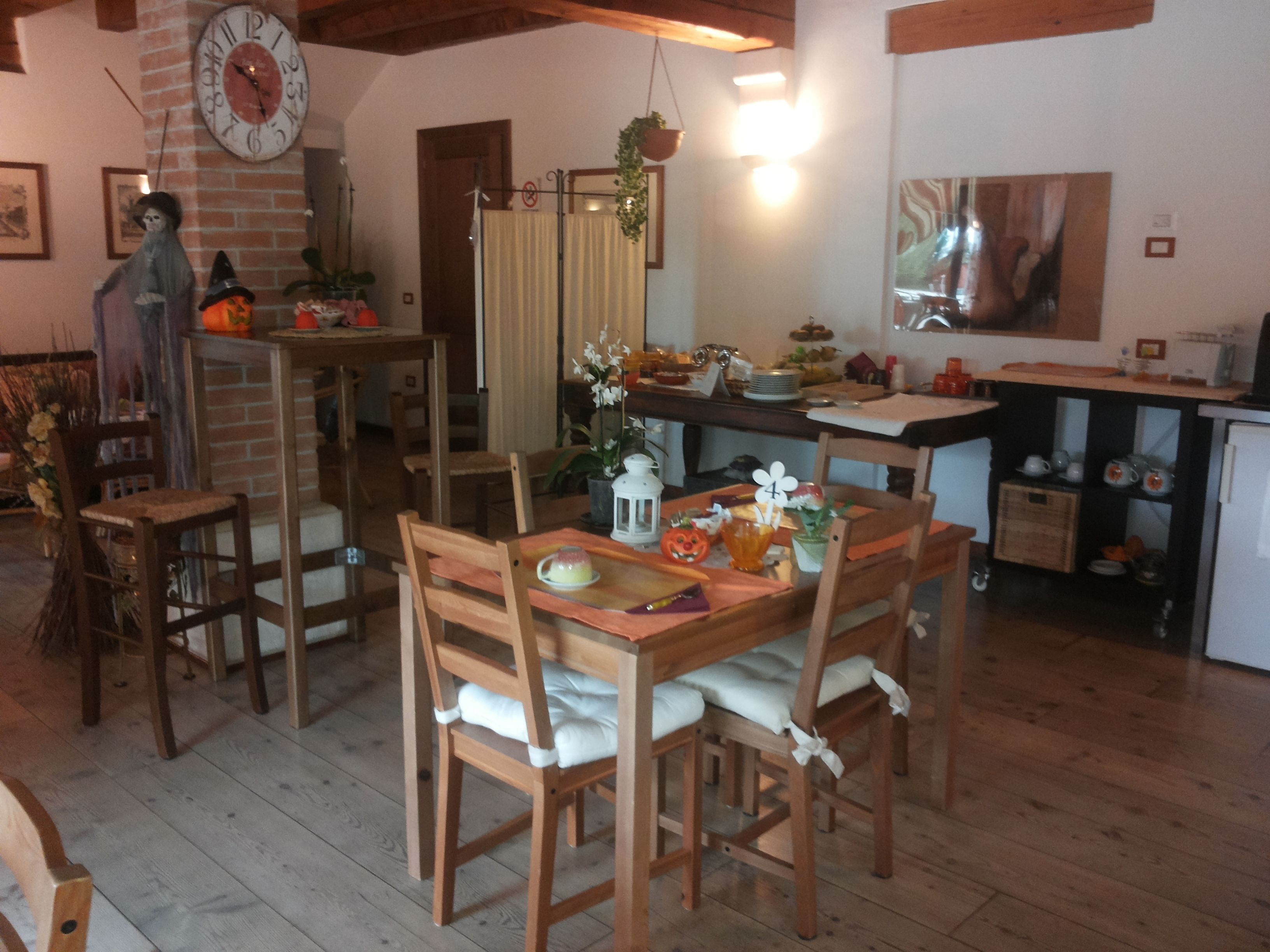 Un rincón acogedor para comer con muebles de madera, un reloj y una zona de cocina con refrigerador y armarios.