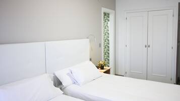 Un dormitorio con cama, mesita de noche, espejo y armario.