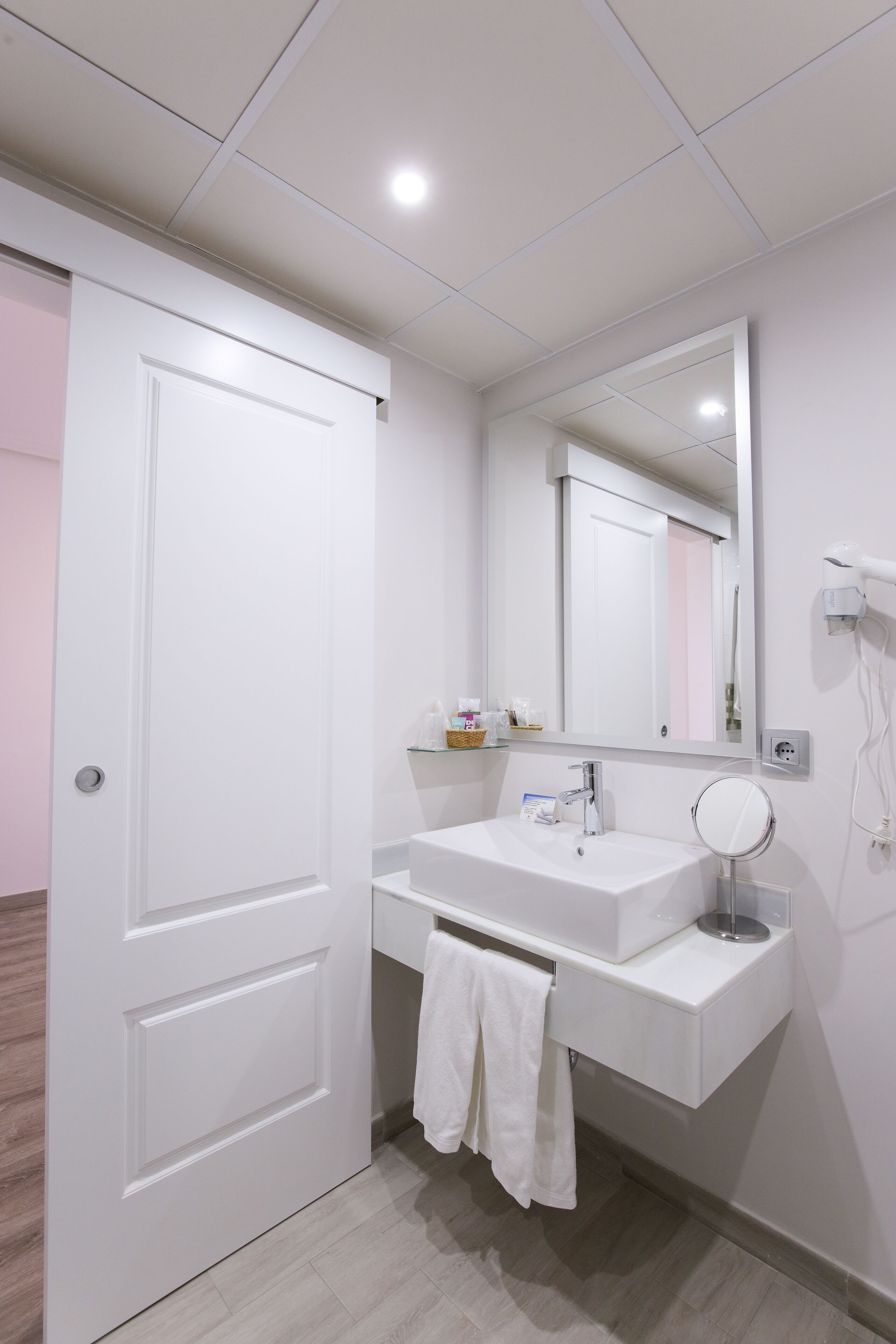 Een moderne badkamer met een wit wastafelmeubel, spiegel en handdoekrek.