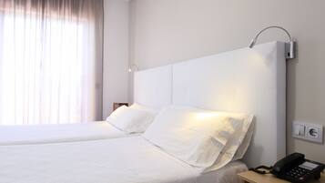 Habitación de hotel con una cama grande, una mesita de noche con un teléfono y una lámpara de pared.
