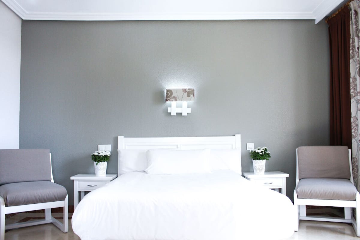 A bedroom with a large bed, two nightstands, and two chairs.