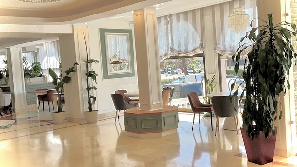 A spacious hotel lobby with a central seating area, large windows with curtains, and potted plants. - Hotel Castilla Torrijos (Torrijos)