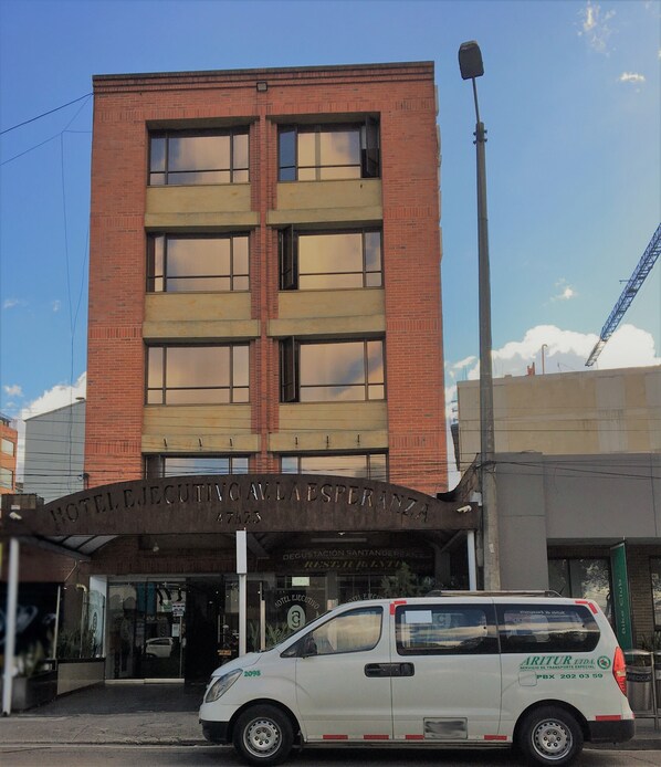 A hotel building with a sign reading "HOTEL EJEUTIVO LA ESPERANZA" and a white van parked in front. - Hotel Ejecutivo Av Esperanza (Bogotá)
