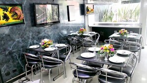 A restaurant with marble walls, multiple tables with chairs, and flower centerpieces. - Hotel Ejecutivo Av Esperanza (Bogotá)