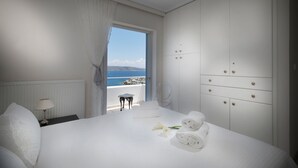 A hotel room with a large bed, a nightstand, a lamp, a view of the sea, and a wardrobe. - Sounio Villa (Lavreotiki)