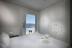 Habitación de hotel con una cama grande, una mesita de noche, una lámpara, vistas al mar y un armario.